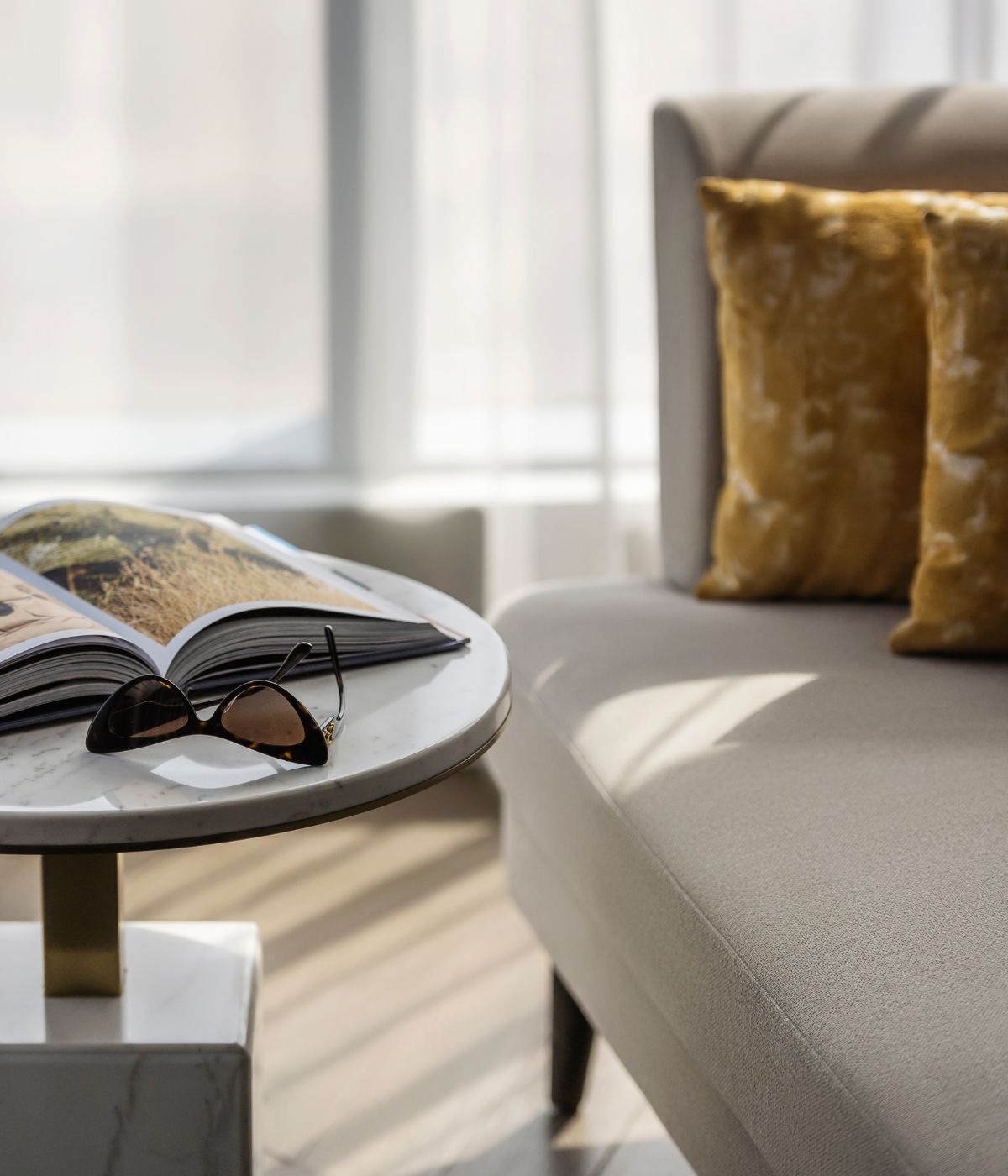 A magazine and sunglasses are placed on a table beside a couch, creating a relaxed living space atmosphere.