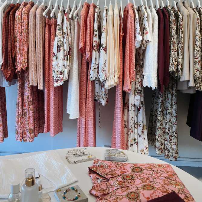 A room filled with a clothing rack displaying various garments in different colors and styles.