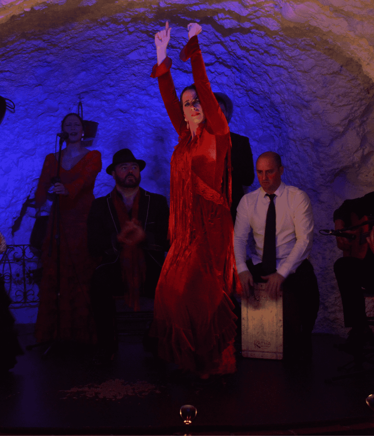A dramatic night scene showcasing a female flamenco dancer in a floral dress facing a rider on a magnificent white Andalusian horse.