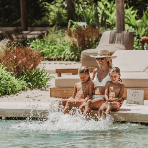 http://A%20woman%20and%20two%20children%20relax%20together%20on%20a%20lounge%20chair%20beside%20a%20swimming%20pool.