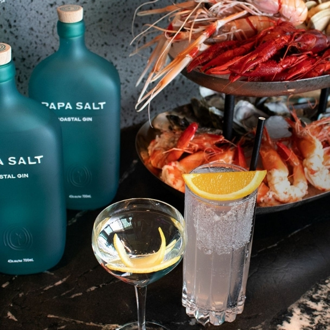 A table displaying a glass of salt water beside a bottle of gin, highlighting a casual drink setup.