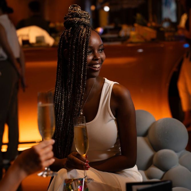 Smiling woman holding a glass of champagne in a warmly lit hotel lounge.