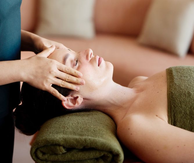 Close-up of a woman receiving a relaxing head and facial massage at a luxury spa.