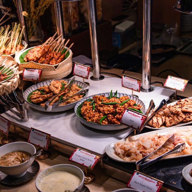 Traditional holiday buffet spread featuring various skewers, fried corn cakes, grilled meat, and dipping sauces.